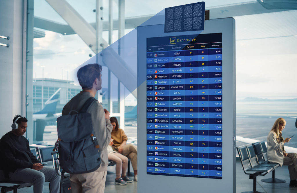 Person looking at a the departure stand at an airport and listening to the information via a directional speaker.